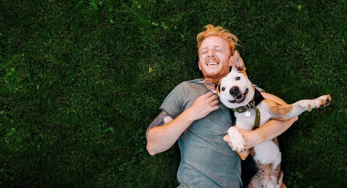 A person happily petting their emotional support dog on a couch, symbolizing affordable housing with an ESA letter.