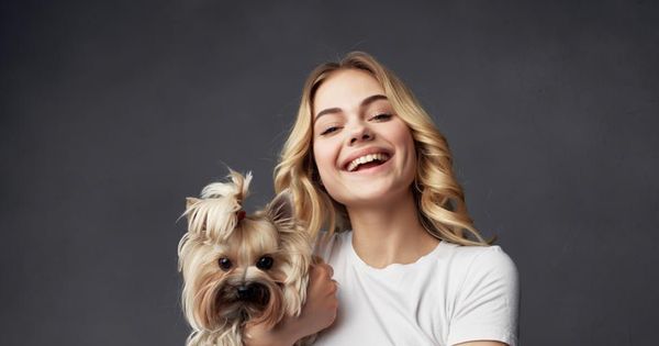A person happily petting a dog on a couch, illustrating the comfort an emotional support animal provides, with a laptop nearby representing online services.